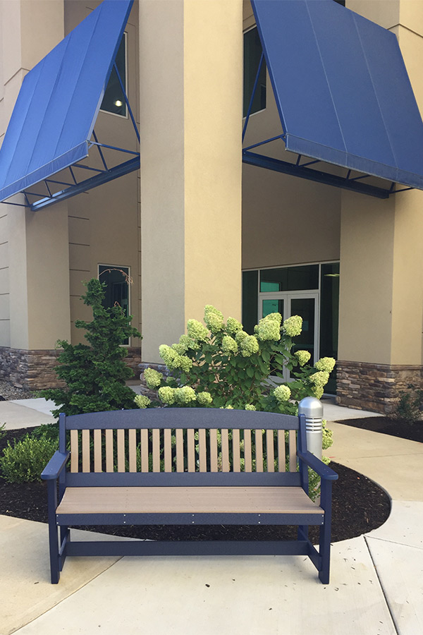 five foot poly garden bench shown in weatherwood on blue